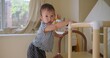 © HarryKiiM Stock - Toddler is mastering standing skills with a play structure in a bright home environment, fostering early childhood development and independent exploration.