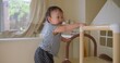 © HarryKiiM Stock - Toddler is mastering standing skills with a play structure in a bright home environment, fostering early childhood development and independent exploration.