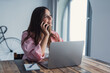 © Daniel - Smiling young lady working at home office desk by laptop engaged in phone conversation with client give remote consultation. Caucasian woman employee make business call from workplace distracted