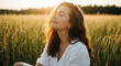 © elkhan - Serene young woman with closed eyes enjoying the golden hour sunlight in a peaceful grassy field.