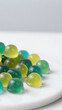 © Tameem - Vibrant green gummies are arranged on a white surface, showcasing their playful colors and shapes. The gummies appear chewy and appealing, with a shallow depth of field emphasizing their details.