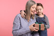 © New Africa - Little girl greeting her grandmother with gift on pink background