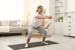 © New Africa - Senior woman exercising on mat at home. Fitness and sport