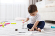 © New Africa - Child safety at home. Little boy playing with pills on floor indoors, space for text