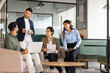 © fizkes - Diverse colleagues gather in office lounge with documents and laptop, discussing business project, brainstorm ideas, planning strategy during corporate teamwork Professional collaboration, partnership