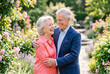 © Meow Creations - Elderly couple sharing joyful embrace in lush garden with roses