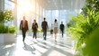 © pkproject - Professionals walk through a sunlit modern office lobby featuring large and lush green plants creating a bright atmosphere of teamwork and corporate innovation
