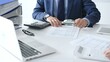 © rogerphoto - Male financial analysts with female colleague examining documents, using magnifying glass and calculator at workplace in office. Audit and taxes in business