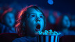 © KIMINI - Excited young child holding popcorn watching movie in dark theater