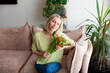 © Tatyana Gladskih - Adult woman with bouquet of tulips sitting on sofa at home, woman was given flowers for her birthday or mother's day