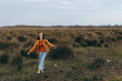 © SHOTPRIME STUDIO - Young woman lifestyle walking outdoors in casual clothes on a field with grass and bushes. Autumn nature background with cloudy sky creates calm and natural mood.
