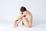 Natural beauty concept, young nude woman with long hair sitting on white background, skincare, body care and wellness