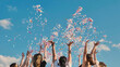 © Довидович Михаил - High school graduates joyfully tossing confetti in the air under a clear blue sky