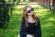 © Довидович Михаил - Teenager with trendy sunglasses and dandelion in hair takes a relaxing break outdoors during school day