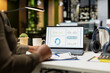 © DC Studio - African american skilled analyst reviewing monthly reports for a new growth strategy, using infographics on laptop to plan resources allocation and align objectives with financial development.