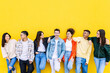 © Xavier Lorenzo - Youth community. Diverse group of friends standing together over yellow wall. Friendship concept