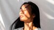 © mila103 - Serene asian female in sunlit bliss with eyes closed.