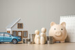 © Garun Studios - Family financial planning concept with house model, car, piggy bank and stacked coins. Represents personal asset management, savings deposit, insurance protection, retirement planning.