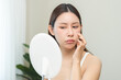 © KMPZZZ - Anti aging, worry puberty asian young woman, stressed girl looking in mirror, allergy presenting an allergic reaction from cosmetic on face. Beauty, health care from acne problem, dry skin, treatment.
