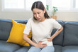 © KMPZZZ - Sick asian young woman in pain, hand holding belly, stomach pain from food poisoning, girl hurt abdomen ache and digestive problem, gastritis or diarrhea. Health care inflammation, abdominal problem