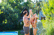 © Halfpoint - Family under shower by the pool on sunny summer day.
