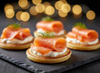 © Jim - Smoked salmon appetizers arranged on slate. Small cornbread cakes topped with cream cheese, salmon, and dill. Cozy bokeh lights add festive atmosphere for parties or events. Gourmet Party Appetizers
