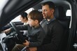 © Serhii - family choosing a car in dealership, they want the most comfortable and safe car
