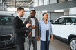 © Serhii - Car salesman showing vehicles to african american couple in dealership