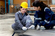 © Stella - Female engineer worker in industrial safety suit and helmet has accident, a heavy metal sheet fell on her foot at manufacturing factory, colleague try to help. Woman leg is trapped under metal sheet.