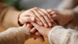 © Denis Yevtekhov - Close-up of multiple faceless people's hands held together showing care, love, and support on a neutral surface, defocused warm background, hands showing love, comfort support gesture, family