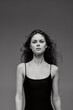 © SHOTPRIME STUDIO - Black and white portrait of a young woman with loose hair wearing a black sleeveless top against a plain background.