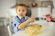 © Tomsickova - Cute preschool child, blond boy, eating spaghetti at home, making a mess everywhere