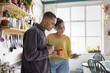 © ReeldealHD images - Couple Enjoying Morning Coffee and looking at a smartphone in a Bright Kitchen