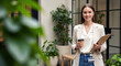 © Alexandr Peers - Clipboard holding office employee with coffee cup standing in workplace corridor, female staff member ready for document review visitor check in or daily administration support at reception