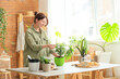 © Pixel-Shot - Young woman with plant and pots on table in workshop