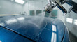 © AiStock B - A professional auto body painter uses a high-precision spray gun to apply a glossy clear coat or a fresh layer of blue paint to a car's hood in a modern and clean workshop.
