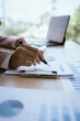 © Worawi - A businesswoman analyzing financial charts and documents while using a calculator, focusing on data review and financial planning in a professional office setting.