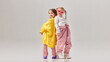 © Lustre Art Group  - Two little girls standing back to back wearing oversized fashionable clothes and high heels in studio. Concept of friendship, childhood confidence, fashion play, creativity and expressive lifestyle.