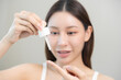 © KMPZZZ - Happy beauty routine, asian young woman, girl dropping collagen moisturizer on her finger from pipette, applying vitamin using oil serum on face moisturizing for hydrating skin, isolated on background