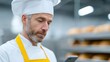 © Business Image - Bäckereimitarbeiter nutzen mobile Technologie zur Dienstplanung in einem geschäftigen deutschen Hinterzimmer