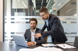 © Liubomir - Two professional businessmen collaborating and sharing ideas while working together on a laptop during an important corporate meeting in a modern office setup
