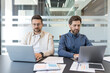 © Liubomir - Two professional businessmen collaborating and focusing on their individual laptops while working at a table in a bright, contemporary office environment