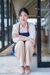 © Tj - Asian woman owner smiling sitting at cafe entrance