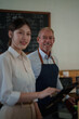 © Tj - Barista owner mentoring young woman business trainee