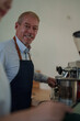 © Tj - Happy senior barista making coffee in cafe