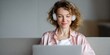 © Andrii Zastrozhnov - Female caucasian adult smiling in headphones while using laptop on sofa, relaxed remote learning or leisure browsing at home