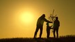 © Victoriia - Gardener, dad mom child plant tree. Family with shovel watering can plants young trees that are sprouting in soil. Family with tree at sunset. Happy family team plants tree in spring sun. Silhouette