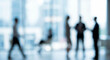© birulaut - A blurred scene of people engaged in conversation within a modern office setting, showcasing a dynamic work environment with various silhouettes.