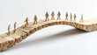 © Sulai - Miniature figures walk across wooden bridge against a white background