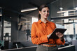 © Stock 4 You - Latin Hispanic mature professional business woman looking at online trade app. European young businesswoman CEO holding digital tablet using fintech tab application standing at workplace in office.